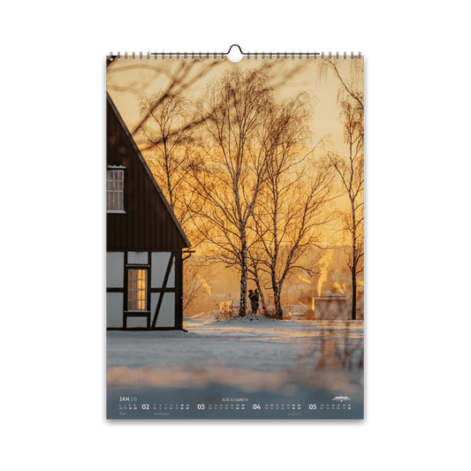 Januar-Motiv des Bergstadtkalenders 2026 im DIN-A3-Hochformat: die Alte Elisabeth in Freiberg an einem frostigen Wintermorgen, mit goldenem Sonnenlicht und Rauchschwaden über der verschneiten Landschaft.