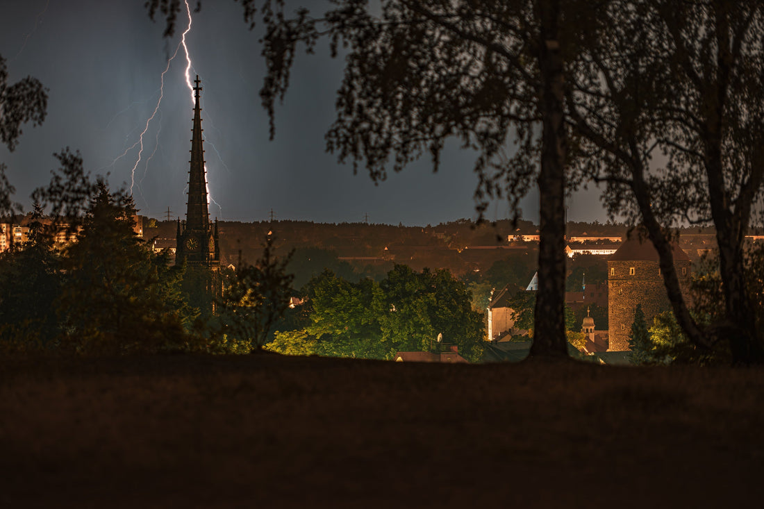 Blitz schlägt neben der Jakobikirche in Freiberg ein, rechts der Nikolaiturm und die Altstadt-Silhouette – Gewitternacht am 1. August 2026
