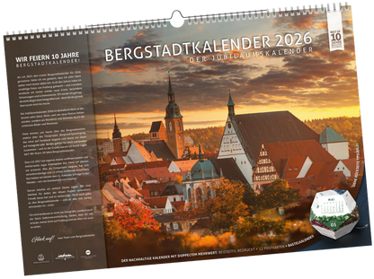 Titelblatt des Bergstadtkalenders 2026 im Format DIN B3 mit Hinweis auf das 10-jährige Jubiläum. Zu sehen ist der Altstadtblick von Freiberg mit Petrikirche und Dom, ergänzt durch den integrierten Bastelkalender in Würfelform.