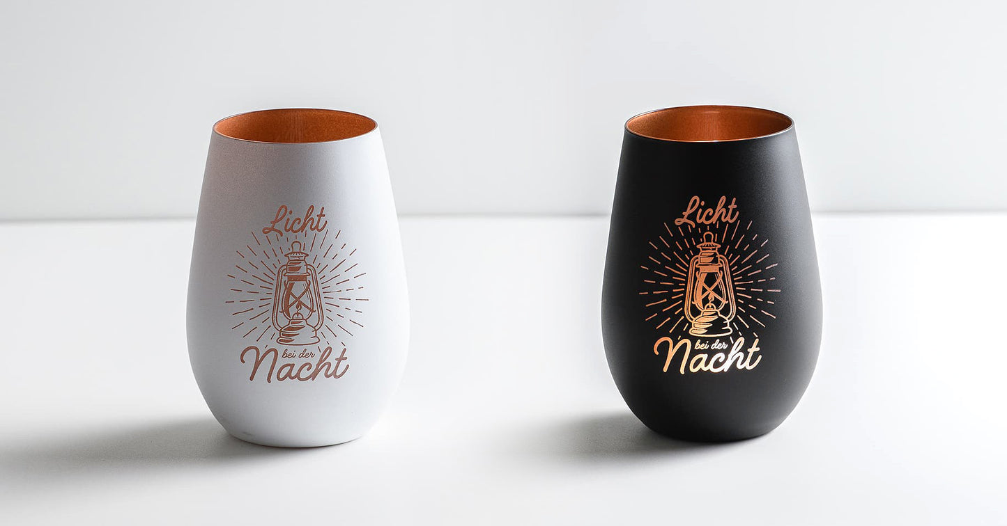 Zwei Windlichter mit dem gelasertem Motiv: Licht bei der Nacht. Gezeigt werden die beiden verfügbaren Farbvarianten