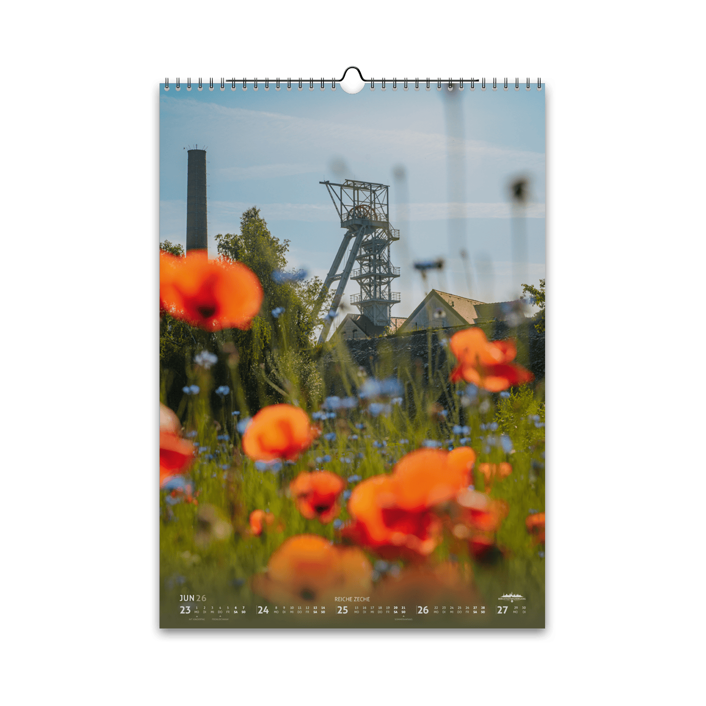 Juni-Motiv des Bergstadtkalenders 2026 im DIN-A3-Hochformat: das Fördergerüst der Reichen Zeche in Freiberg, umgeben von leuchtend roten Mohn- und blauen Kornblumen auf einer Sommerwiese.