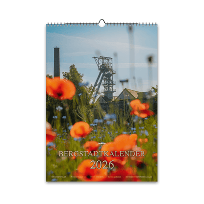 Titelmotiv des Bergstadtkalenders 2026 im DIN-A3-Hochformat mit dem Förderturm der Reichen Zeche in Freiberg, umgeben von leuchtenden Mohn- und Kornblumen.