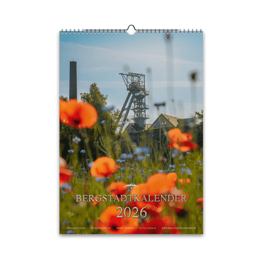 Titelmotiv des Bergstadtkalenders 2026 im DIN-A3-Hochformat mit dem Förderturm der Reichen Zeche in Freiberg, umgeben von leuchtenden Mohn- und Kornblumen.
