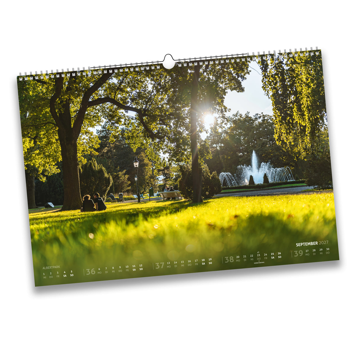 Kalenderblatt September 2027: Sonniger Spätsommertag im Albertpark Freiberg mit Springbrunnen und Besuchern im Gras.
