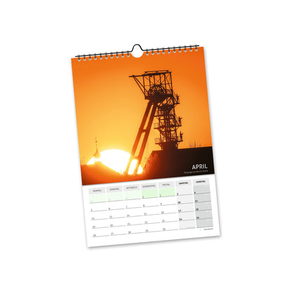 April 2027: Silhouette eines Freiberger Fördergerüsts vor orangefarbenem Himmel bei Sonnenuntergang.