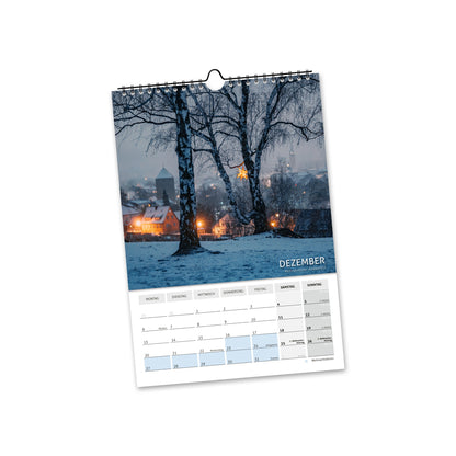 Dezember 2027: verschneite Bäume vor der beleuchteten Freiberger Altstadt in winterlicher Abendstimmung.