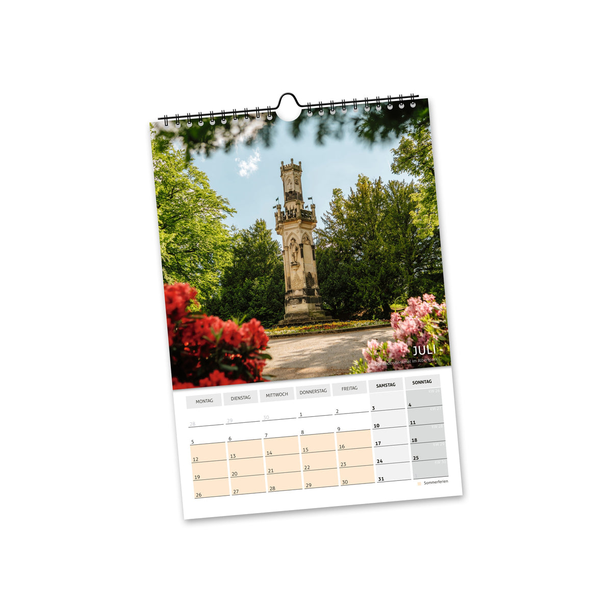Juli 2027: steinernes Denkmal zwischen Rosen und grünen Bäumen in Freiberg.