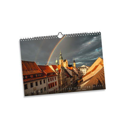 September 2027: Regenbogen über der Petrikirche und den roten Dächern der Freiberger Altstadt unter dunklen Wolken.