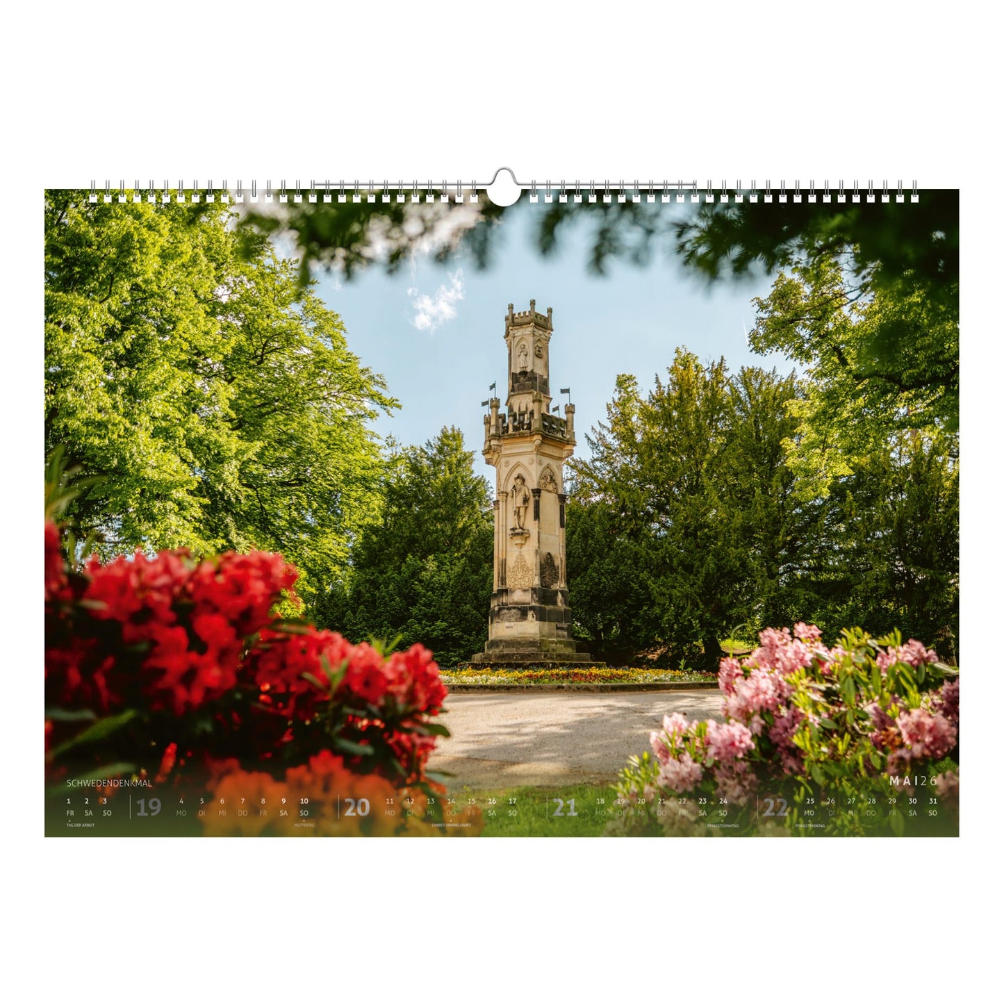 Das Schwedendenkmal im Albertpark Freiberg, umrahmt von blühenden Rhododendronbüschen – ein stimmungsvolles Frühlingsmotiv im Bergstadtkalender 2026.