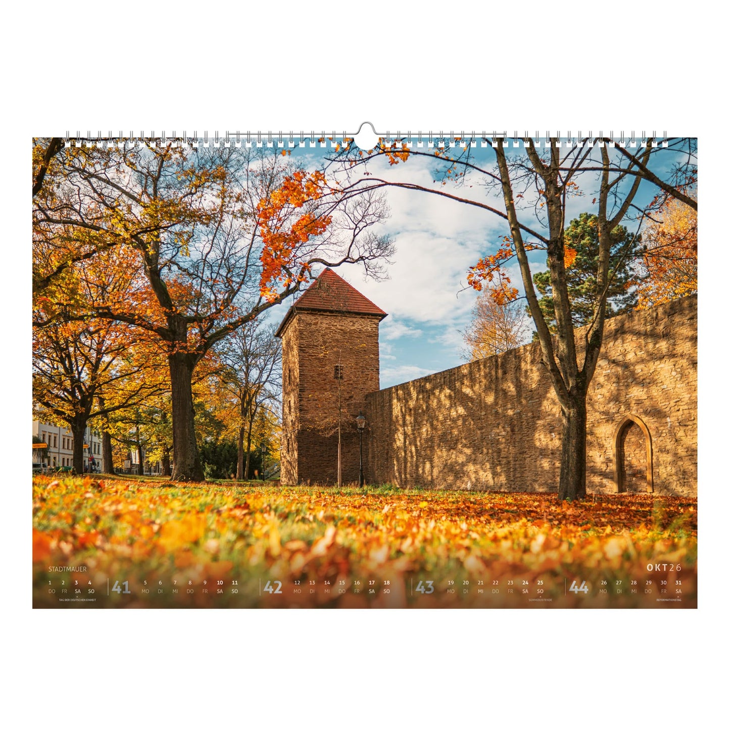 Herbstliche Szene an der Freiberger Stadtmauer mit Gelber Löwe Turm und buntem Laub, historischen Mauern und Türmen – Kalenderbild aus dem Bergstadtkalender 2026.