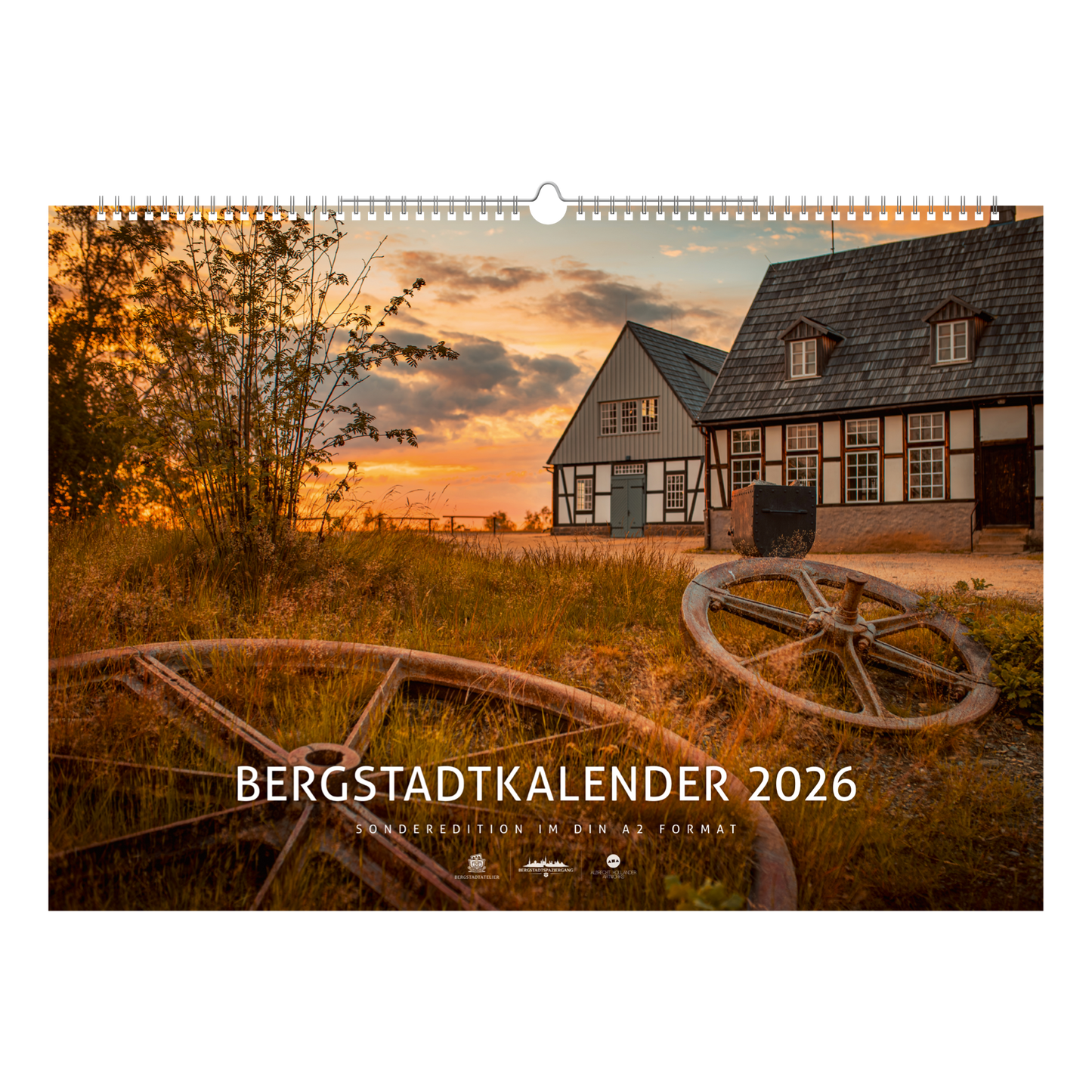 Titelblatt des Bergstadtkalenders 2026 im Sonderformat mit der Alten Elisabeth in Freiberg im warmen Licht des Sonnenuntergangs – historische Bergwerksgebäude mit Seilscheiben im Vordergrund.