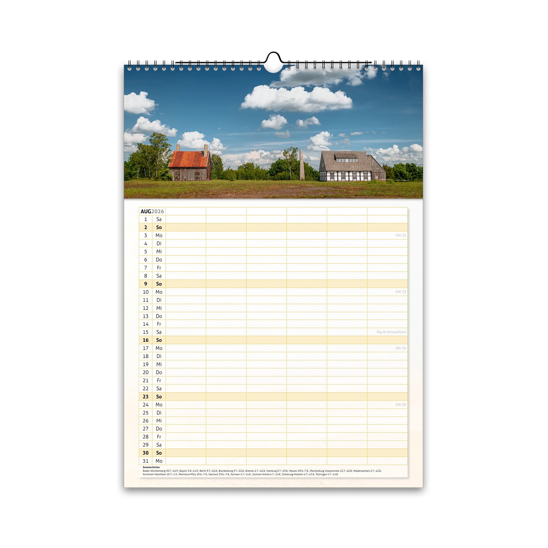 August-Motiv des Familienplaners 2026: die historischen Gebäude des Haldengebäude der Alten Elisabeth bei Freiberg unter blauem Sommerhimmel und grünen Wiesen.