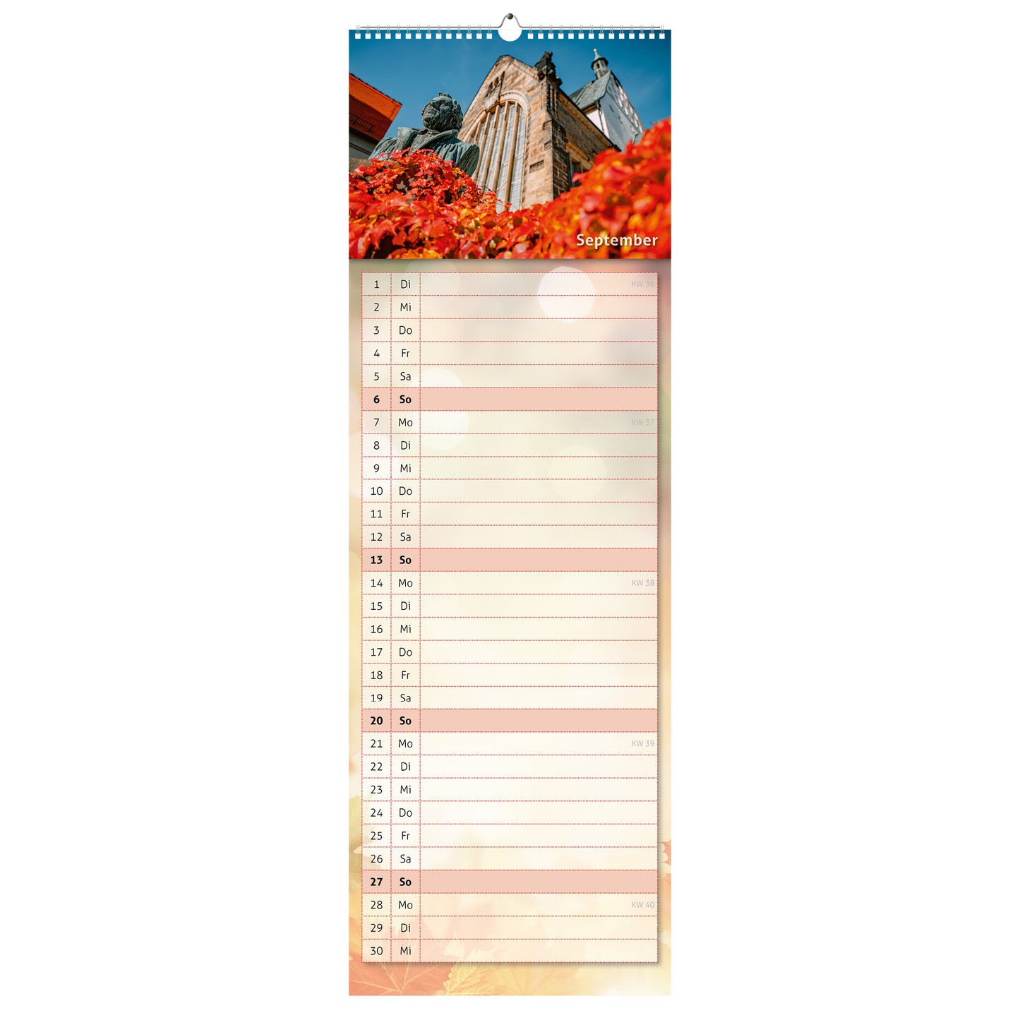 September-Motiv des Küchenkalenders 2026: der Lutherbrunnen vor der Freiberger Goldenen Pforte, umgeben von rot-goldenem Herbstlaub und strahlend blauem Himmel.