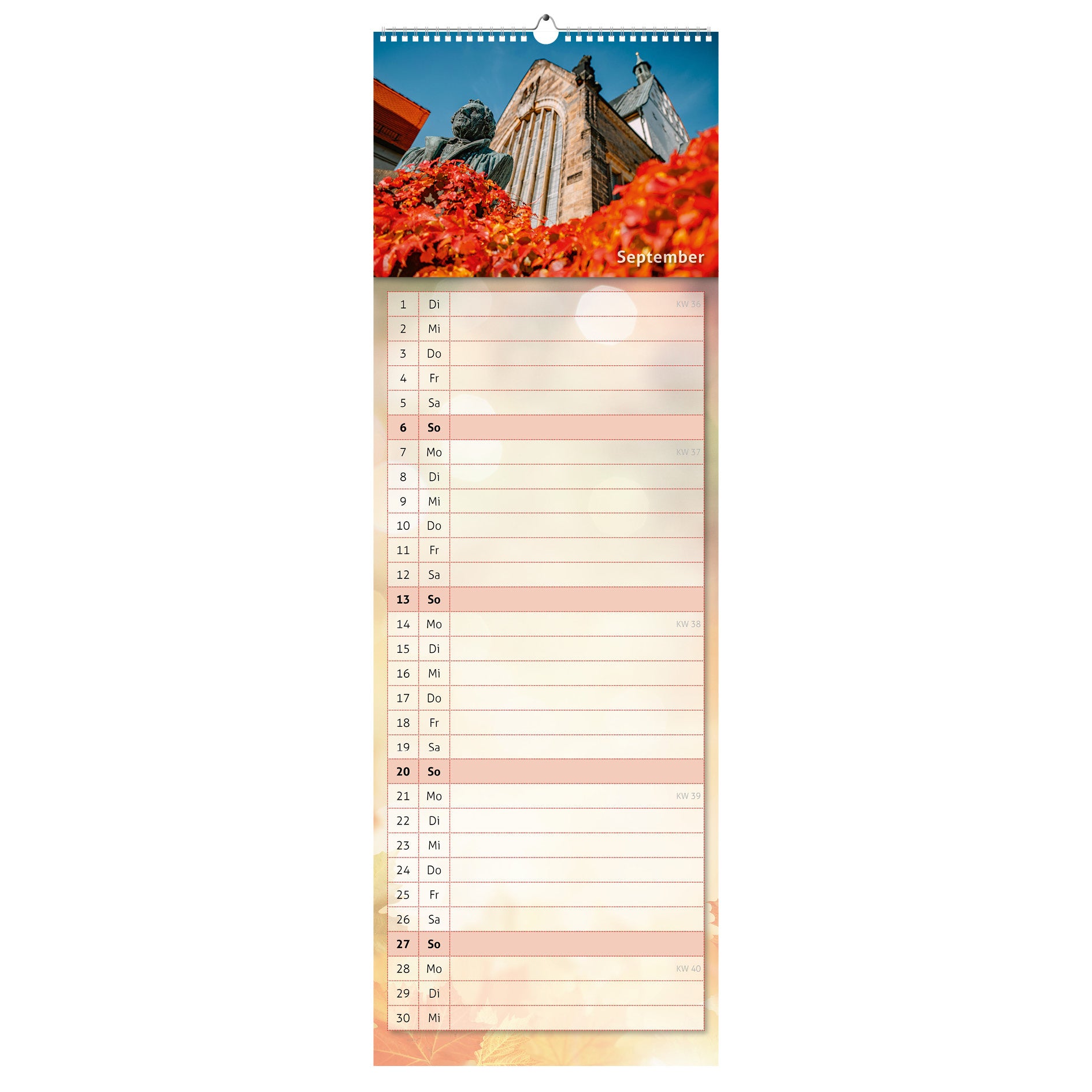 September-Motiv des Küchenkalenders 2026: der Lutherbrunnen vor der Freiberger Goldenen Pforte, umgeben von rot-goldenem Herbstlaub und strahlend blauem Himmel.