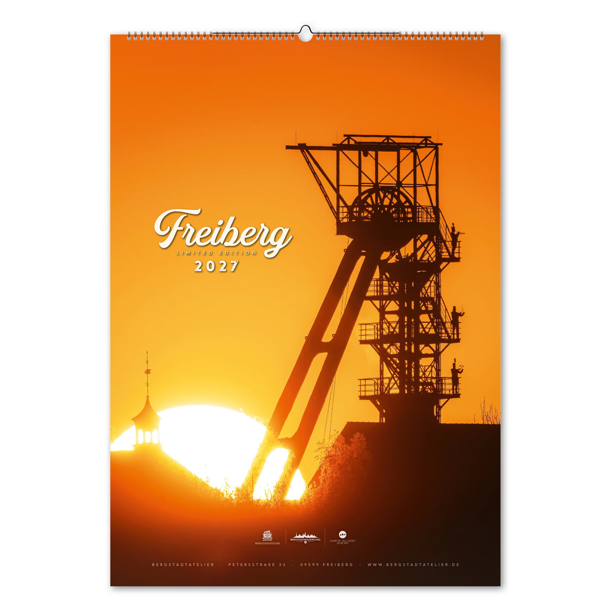Titelblatt des Kalenders Freiberg Limited Edition 2027: Fördergerüst und mehrere Bergmänner als Silhouetten vor orangegelbem Himmel und aufgehender Sonne.