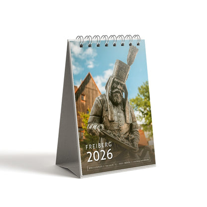 Tischkalender Freiberg 2026 im DIN A6 Format, Titelblatt mit Statue des Bergmanns vom Silberweg am Schüppchenberg vor blauem Himmel und Häusern im Hintergrund. 